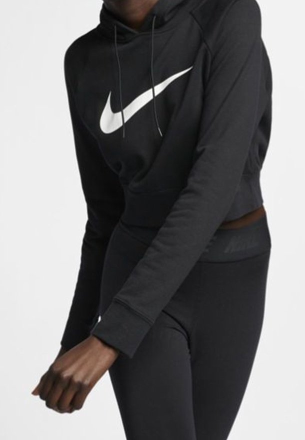 Černá zkrácená mikina vyrobená z hladkého fleecu s velkým bílým logem Nike swoosh na přední straně. Kombinováno s černými legínami s decentním logem.