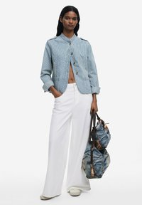 Denim jakna plave i bijele pruge s okruglim ovratnikom, zatvaranjem na gumbe i bočnim džepovima, uparen s širokim bijelim hlačama i dvije denim torbe.