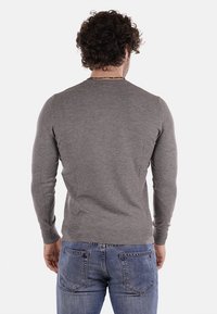 Maglione grigio a maglia con maniche lunghe e scollatura rotonda, abbinato a jeans blu, che mostra una texture liscia e semplice sul retro.
