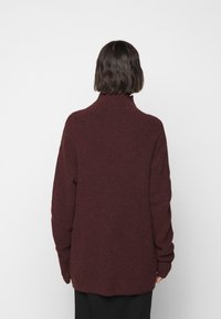 Pull col roulé bordeaux en maille texturée, coupe décontractée, manches longues et col haut. L'ourlet est légèrement arrondi à l'arrière.