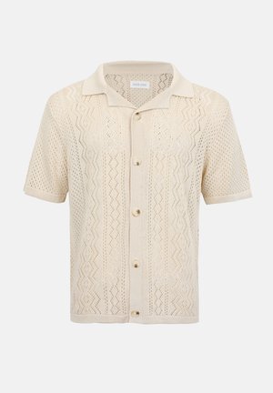 Cardigan beige en maille à manches courtes avec col, boutons à l'avant et motif texturé en zigzag et losanges.
