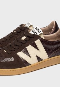 Brązowe zamszowe i teksturowane skórzane sneakersy z kremowymi akcentami, okrągłymi sznurówkami i gumową podeszwą. Posiadają logo na języku i kontrastowe wzory.