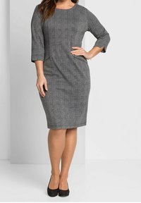 Robe à carreaux grise avec manches trois-quarts, dotée de poches latérales zippées. Texture lisse avec une coupe ajustée et un ourlet à hauteur du genou.