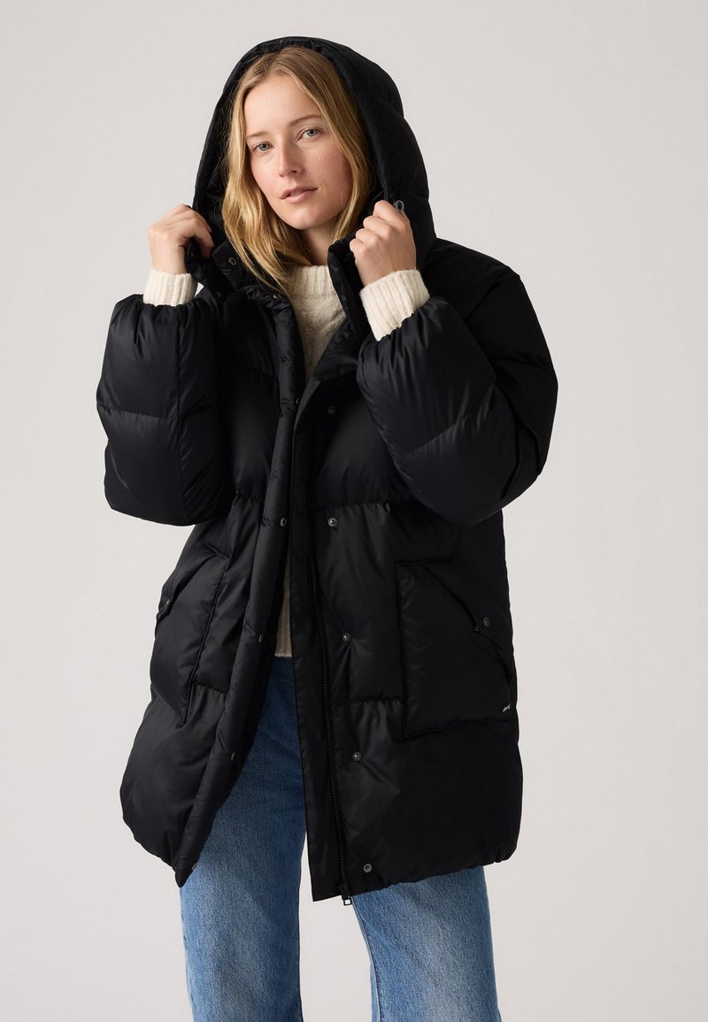 Black puffer coat with a hood, featuring a zippered front, snap buttons, and two side pockets. The material has a smooth, matte texture.