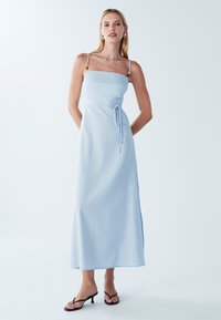 Vaaleansininen, hihaton maksimekko, jossa on muotoiltu bodice, säädettävä nauhavyötärö ja sivurei'itykset. Materiaalissa on hienovarainen rakenne.