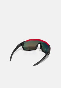 Sportsonnenbrille mit einem schwarzen und roten Kunststoffrahmen. Grünstichige Gläser. Winkliges Design, umschließender Stil und gebogene Bügel für einen sicheren Sitz.