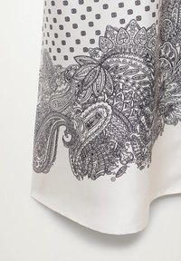 Tessuto bianco con intricati motivi paisley neri e floreali lungo il bordo e un piccolo motivo a pois sopra.