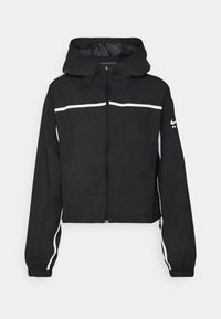 Veste noire courte avec capuche, dotée d'une fermeture éclair devant, de rayures horizontales blanches et de poignets élastiques. Fabriquée en tissu léger et texturé.