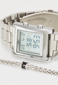 Montre numérique à bracelet en acier inoxydable, cadran carré, deux boutons poussoirs et un écran LCD clair. Inclut un bracelet en chaîne torsadée argentée.