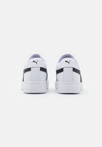 Fehér sneaker, sima bőrborítással, fekete kiegészítőkkel az oldalán és párnázott nyakkal. Texturált gumitalp.