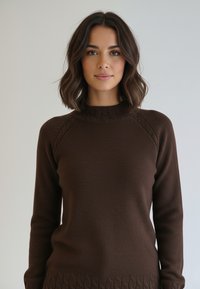 Brązowy dziany sweter z prążkowanym kołnierzem, teksturowanymi szwami na ramionach i wzorzystym obrzeżem. Tkanina wydaje się miękka i ciepła.