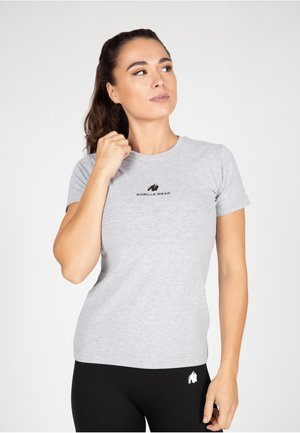 Grijze T-shirt met korte mouwen van een katoenmix met een zwart "GORILLA WEAR" logo op de borst. Model draagt een aansluitende zwarte legging.