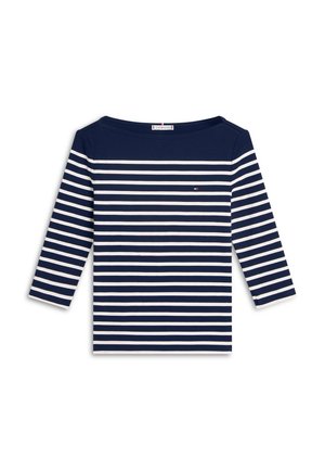 Μπλε ναυτικό μακρυμάνικο μπλουζάκι με οριζόντιες λευκές ρίγες, λαιμόκοψη σε σχήμα βάρκας και μικρή λεπτομέρεια λογότυπου στο στήθος. Ομαλή υφή βαμβακερού υφάσματος.