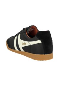 Sneaker in pelle nera con strisce bianche, suola in gomma e tallone in suede nero. Presenta dettagli con marchio e un interno arancione imbottito.