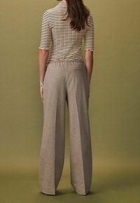 Gestreept top met korte mouwen en geschulpte randen, gecombineerd met beige hoge taille wijde broek van textuurstof, voorzien van een achterzak.