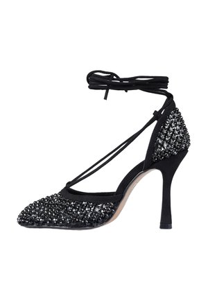 Scarpa nera con tacco alto, punta appuntita, cinturini avvolgenti alla caviglia e decorazioni in cristallo nero su punta e tallone.