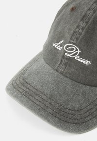 Grey cotton baseball cap with brown stitching and white embroidered text "Les Deux" on the front panel.