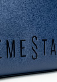 Modrá texturovaná kožená taška s černým embosovaným textem "EXTREME STAR" na přední straně. Má hladký povrch a strukturovaný tvar.