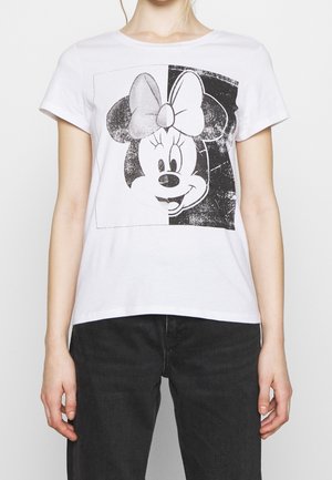 White t-shirt with black and white split graphic of Minnie Mouse's smiling face wearing a bow, worn with black pants.