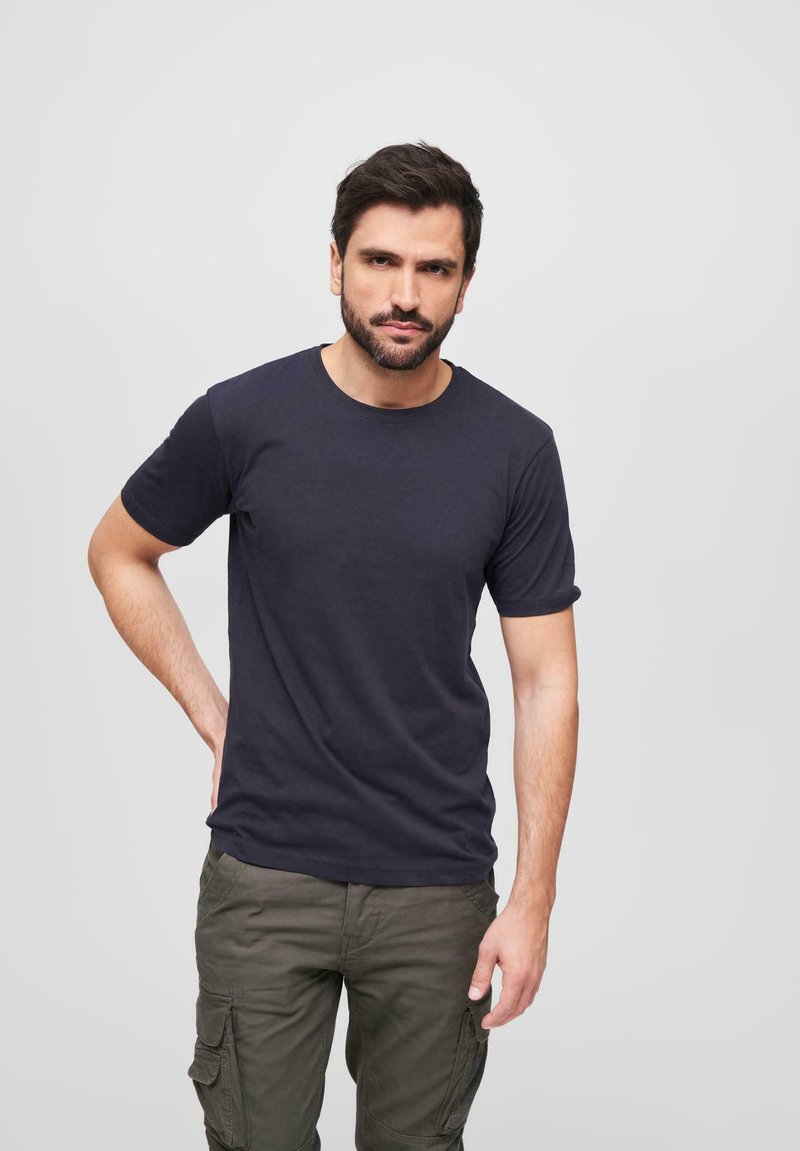 Navy modrá bavlněná tričko s krátkým rukávem a kulatým výstřihem, kombinované s olivově zelenými cargo kalhotami s několika kapsami.