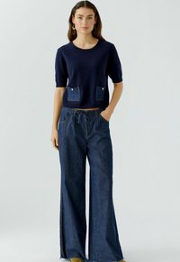 Marine gebreid top met korte mouwen en twee denim patch zakken; wijde denim broek met een gerafeld zoom en een tailleband met trekkoord.