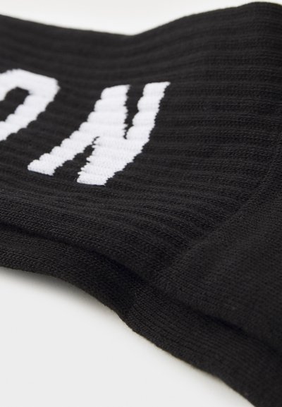 Tejido de punto negro con una textura acanalada, que presenta letras blancas en negrita. Los bordes son lisos con un acabado limpio.