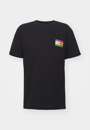 Schwarzes Baumwoll-T-Shirt mit kurzen Ärmeln, das einen mehrfarbigen Logo-Patch mit der Aufschrift "TOMMY JEANS" auf der linken Brustseite zeigt. Gerader Saum.