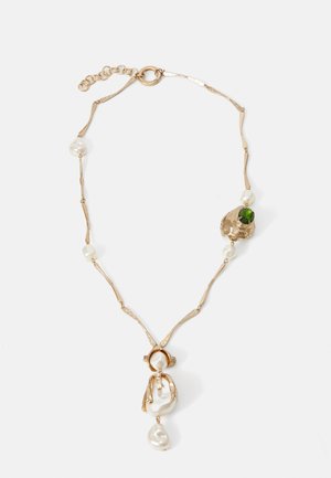 Collier chaîne en or avec des perles irrégulières et une pierre précieuse verte sertie dans un pendentif ornemental en or sur fond blanc.