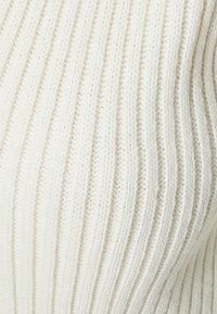 Tessuto a maglia a coste di colore bianco sporco, che presenta linee verticali prominenti e una texture morbida. I dettagli includono cuciture sottili.