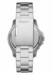 Montre en acier inoxydable argenté avec un fini brossé, dotée d'un bracelet à maillons et d'une fermeture avec le nom de la marque "Fossil" estampé.