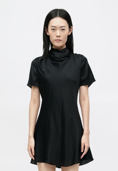 Kurzes schwarzes Kleid aus glattem, leichtem Stoff mit einem Cowl-Ausschnitt und kurzen Ärmeln, das einen leicht ausgestellten Saum hat.