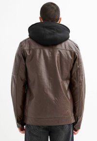 Chaqueta de piel marrón con capucha negra. Presenta acentos de hombros acolchados, textura suave y cierre a presión en la cintura. Vista trasera.