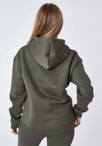 Felpa verde oliva con cappuccio regolabile, polsini e orlo a coste. Tessuto morbido con una superficie texture. Vista da dietro, che mostra il design completo.
