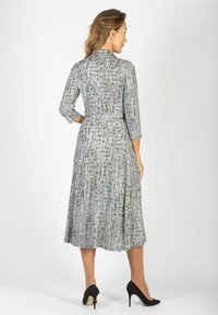 Szara sukienka w wzory z rękawami o długości trzech ćwierć, z paskiem w talii i rozkloszowanym dołem, wykonana z lekkiego materiału, charakteryzująca się płynąca teksturą.