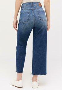 Blaue Jeans aus Denim mit hoher Taille und weitem Bein. Verfügt über zwei Gesäßtaschen und ein Lederetikett am Bund. Mit strukturierter Oberfläche.