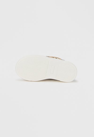 Λευκή λαστιχένια σόλα παπουτσιού με ζιγκ-ζαγκ σχέδιο πέλματος και κεντρικό λογότυπο. Οι άκρες είναι ανυψωμένες, παρουσιάζοντας ομαλό, στρογγυλεμένο σχήμα.