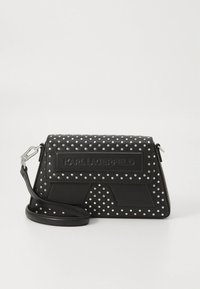 Črna usnjena torbica z srebrnimi našitki v obliki pik, z zaponko na poklopcu in odstranljivim naramnim trakom z logotipom Karla Lagerfelda.