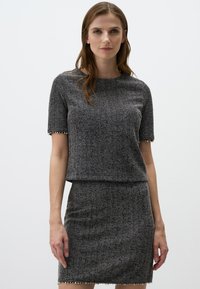 Haut gris en tricot à manches courtes avec un motif texturé, associé à une jupe ajustée assortie avec des accents ressemblant à des perles le long des bords.