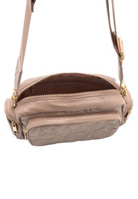 Kleine beigefarbene Handtasche mit strukturierter Oberfläche, goldenen Beschlägen, mehreren Reißverschlussfächern und einem geprägten Logo auf der Vorderseite.