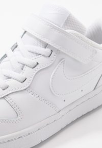 Le sneaker bianche Nike presentano una tomaia in pelle liscia con dettagli in rete, lacci rotondi, una fascia in Velcro e una suola in gomma.