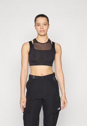 Svart sports-bh med et gjennomsiktig mesh-panel, brede stropper og en cropped design, sammen med svarte cargo-bukser med sidelommer.