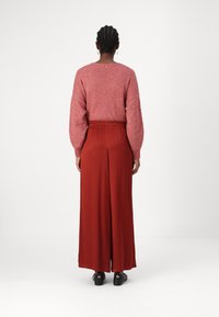 Rode lange rok met een ontspannen pasvorm, elastische tailleband en zijslitsen, gecombineerd met een roze fuzzy trui met pofmouwen.