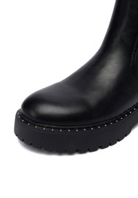 Melna ādas potīšu zābaki ar noapaļotu purngalu, masīvu melnu gumijas zoli un sudraba kniedēm gar malu. Gluda virsma.