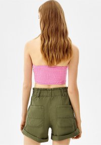 Sydd rosa smockad bandeau topp som matchas med olivgröna shorts med upprullad fåll, stora fickor och resårmidja.