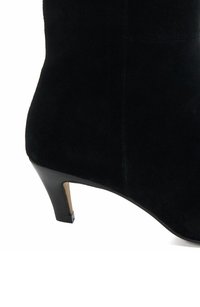Bottes de cheville en suède noir avec une silhouette effilée, petit talon, texture lisse et design minimaliste. Les accents comprennent un détail de talon métallique.