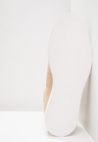 Beżowe zamszowe buty z gładką cholewką, posiadające białą gumową podeszwę. Zaprojektowane w smukłym stylu z minimalnymi detalami. Rozmiar 42.