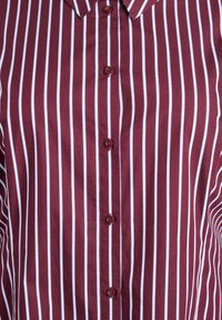 Bordowa koszula z guzikami, w pionowe białe paski, z wyraźnym kołnierzykiem, gładką teksturą i sześcioma pasującymi guzikami z przodu.