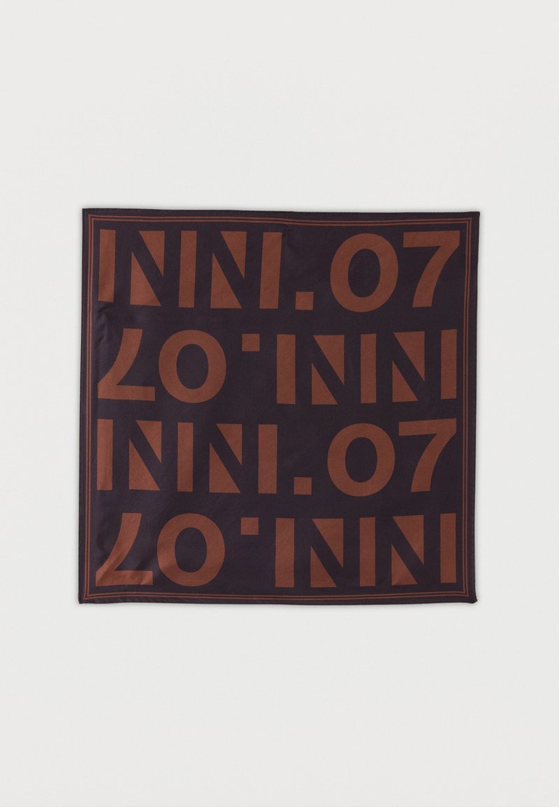 Τετράγωνο από σκοτεινό ύφασμα με επαναλαμβανόμενο μεγάλο καφέ κείμενο "INI.07" και λεπτό καφέ περίγραμμα σε ανοιχτό φόντο.