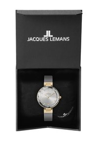 Reloj plateado con un dial texturizado, acentos en dorado y una correa de malla, presentado en una caja negra con el nombre de la marca "Jacques Lemans."