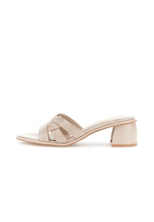 Beżowy, otwarty sandał mule z plecionymi skórzanymi paskami i niskim, masywnym obcasem na białym tle.